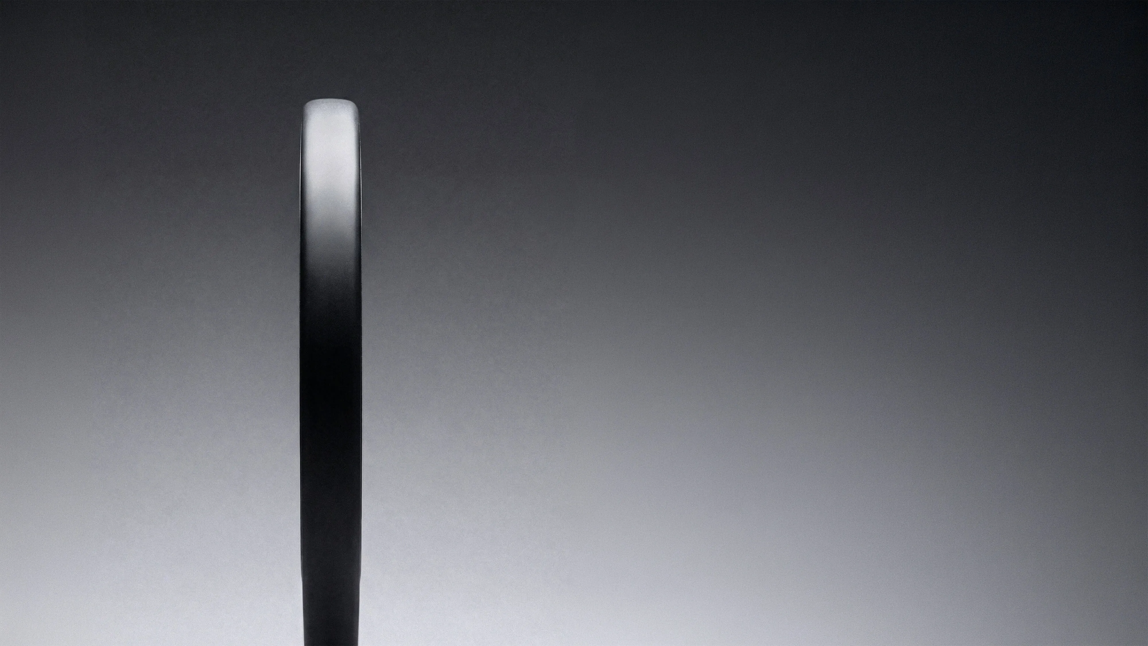 A black, vertical rectangular shape with a rounded top on a grey gradient background.